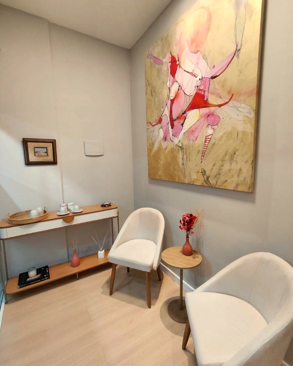 Recepção da Salinha, com poltronas claras, aparador e um quadro de bailarina